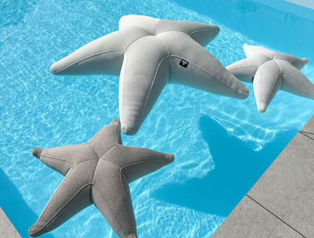 Drei sternförmige Kissen schwimmen in einem blauen Pool.